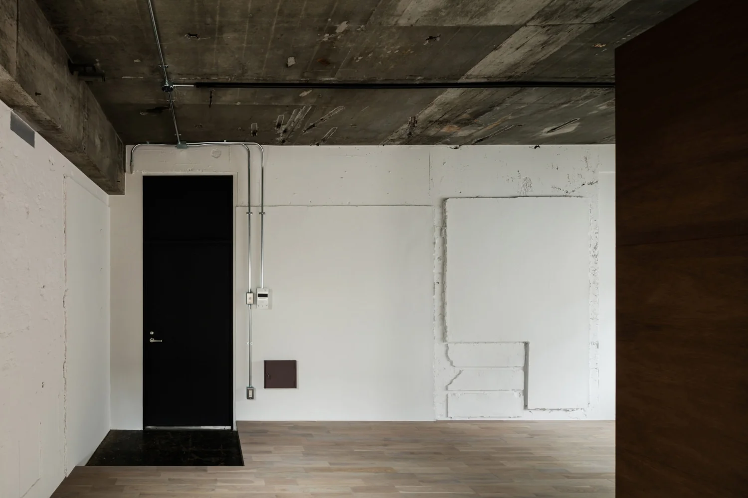 Walls painted in situ, preserving the existing structural relief; floors are oak planks stained a smoke tone.