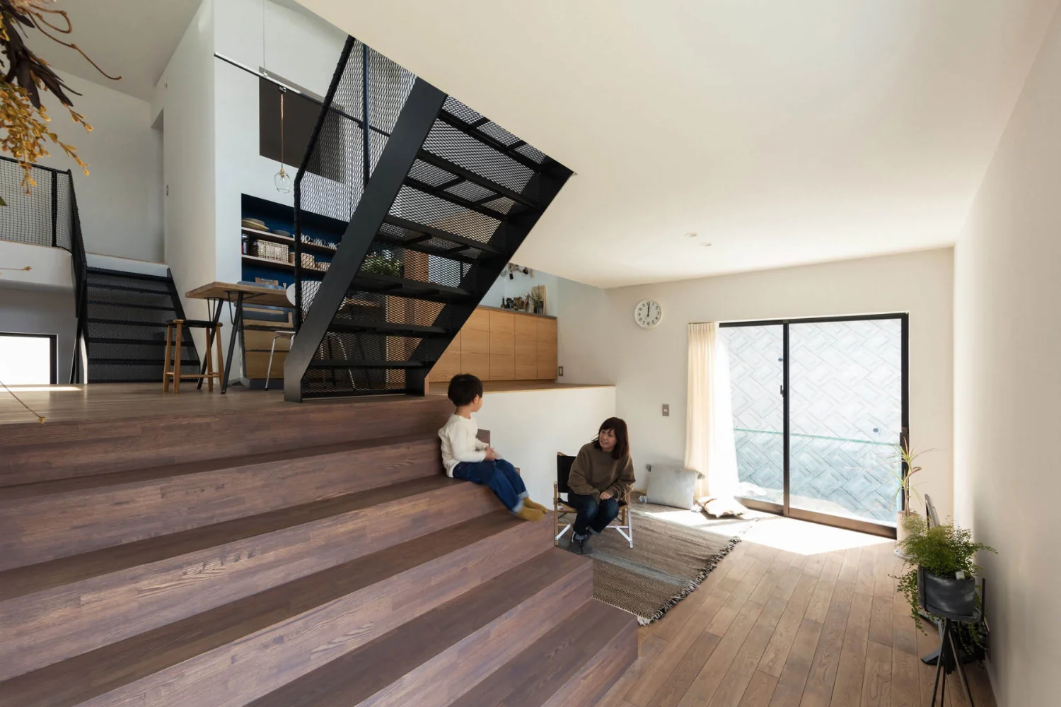 Living room featuring a large staircase. At a half level above, the four‑corner space contains the dining kitchen.｜House of Four Pavilions and an Alley | Four-Corner House