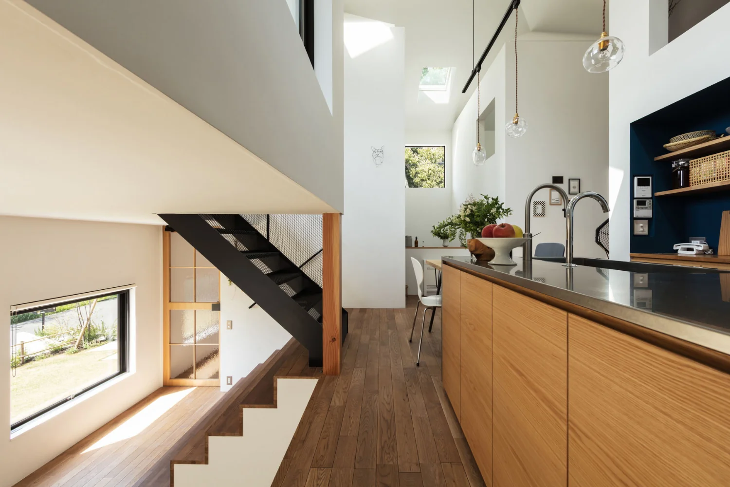 View toward the four‑corner space from the kitchen. The kitchen countertop is stainless steel with a vibratory finish.