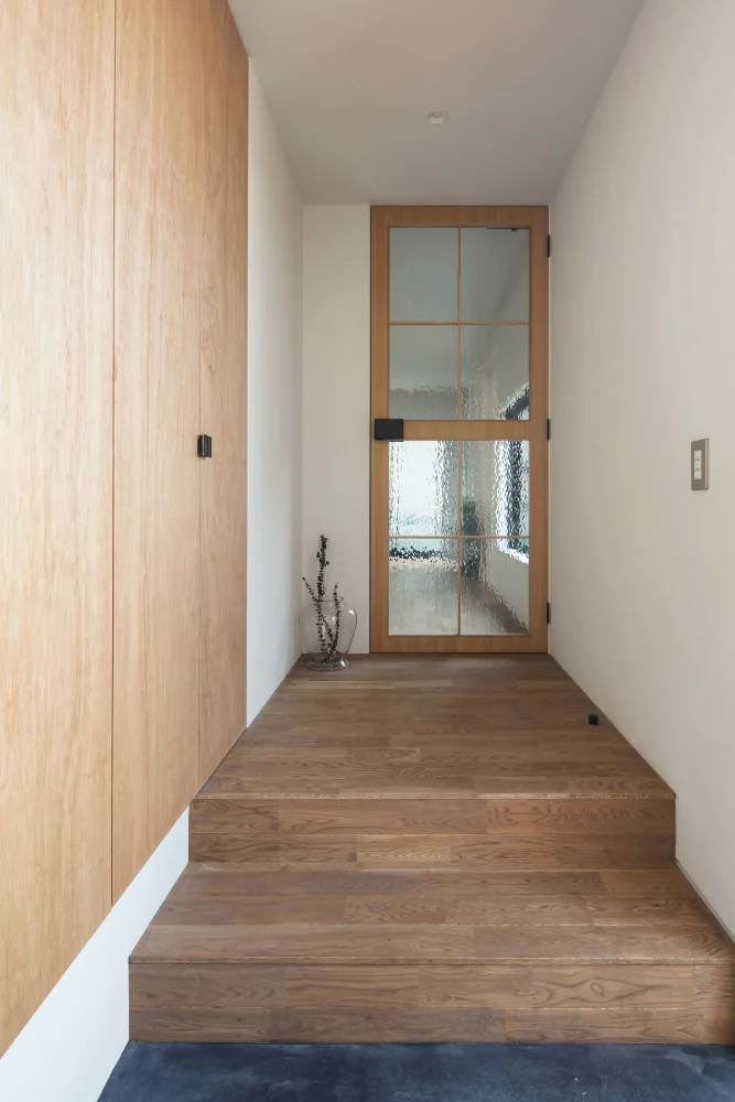 A door fitted with antique glass panels serves as the entrance to the living room.｜House of Four Pavilions and an Alley | Four-Corner House