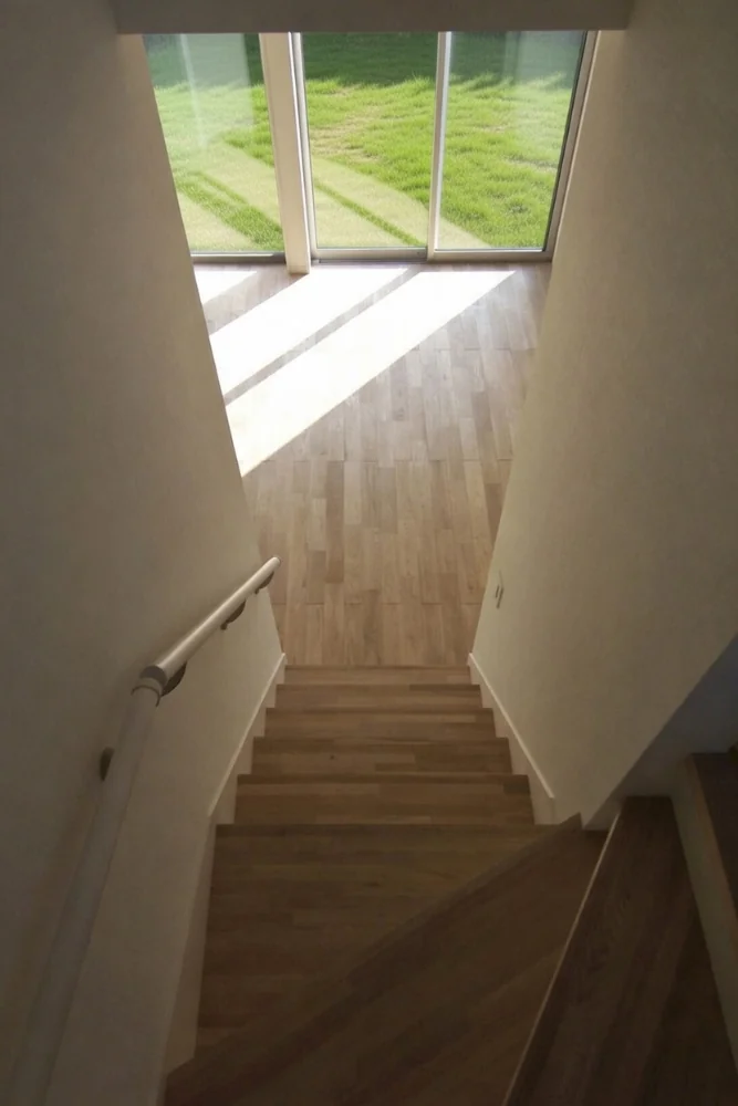 View looking down the stair. Following negotiation with the developer, solid hardwood flooring was adopted; the handrail is an off-the-shelf component.｜Designed Within Prescribed Building Conditions | The Box House