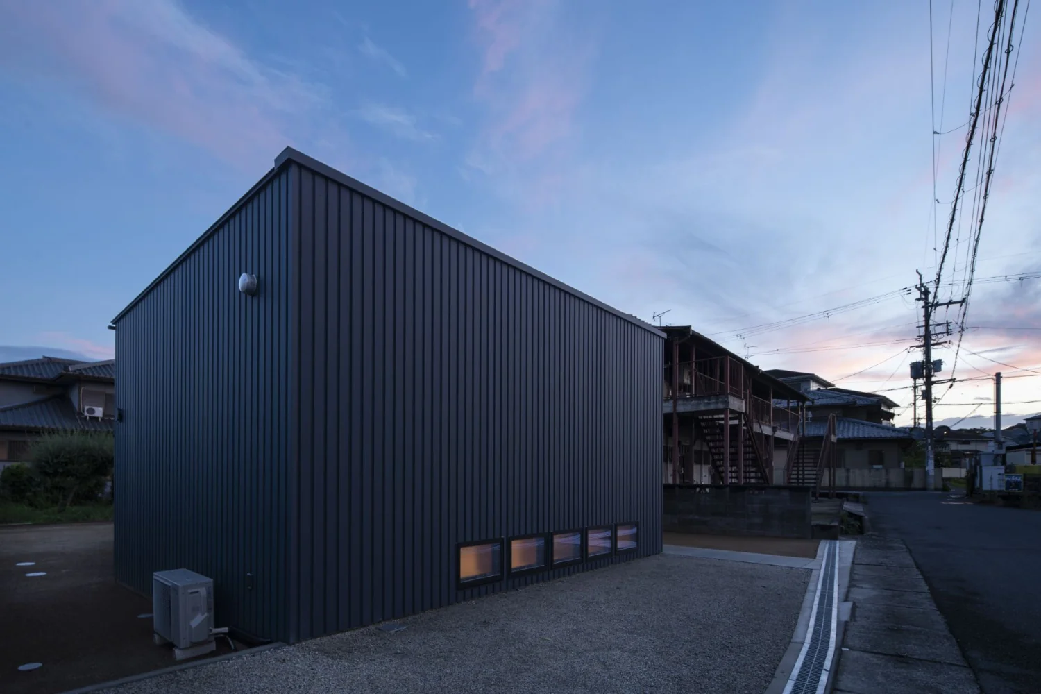 View from the northeast. The site plan responds to constraints by avoiding fire-spread lines and the existing septic tank.｜A Small House Composed of Three Connected Boxes (Large, Medium, Small) | Tsuzura House