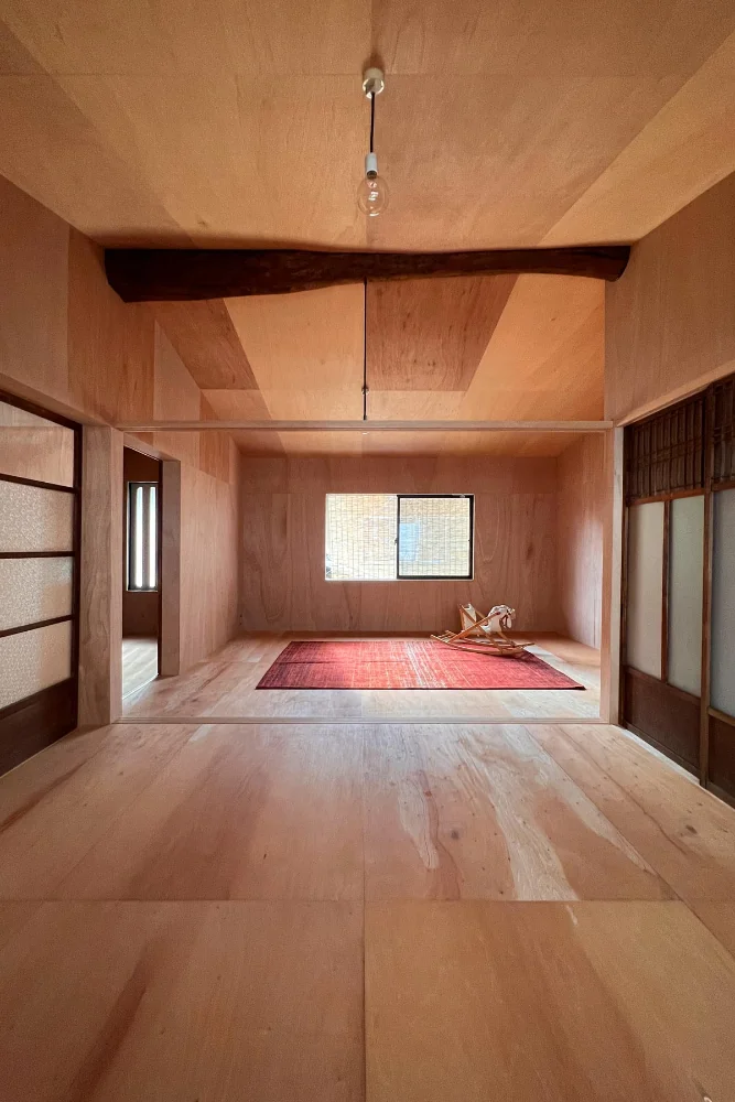 A large round ridge beam is left exposed and the kamoi (lintel) is suspended from it by bolts.