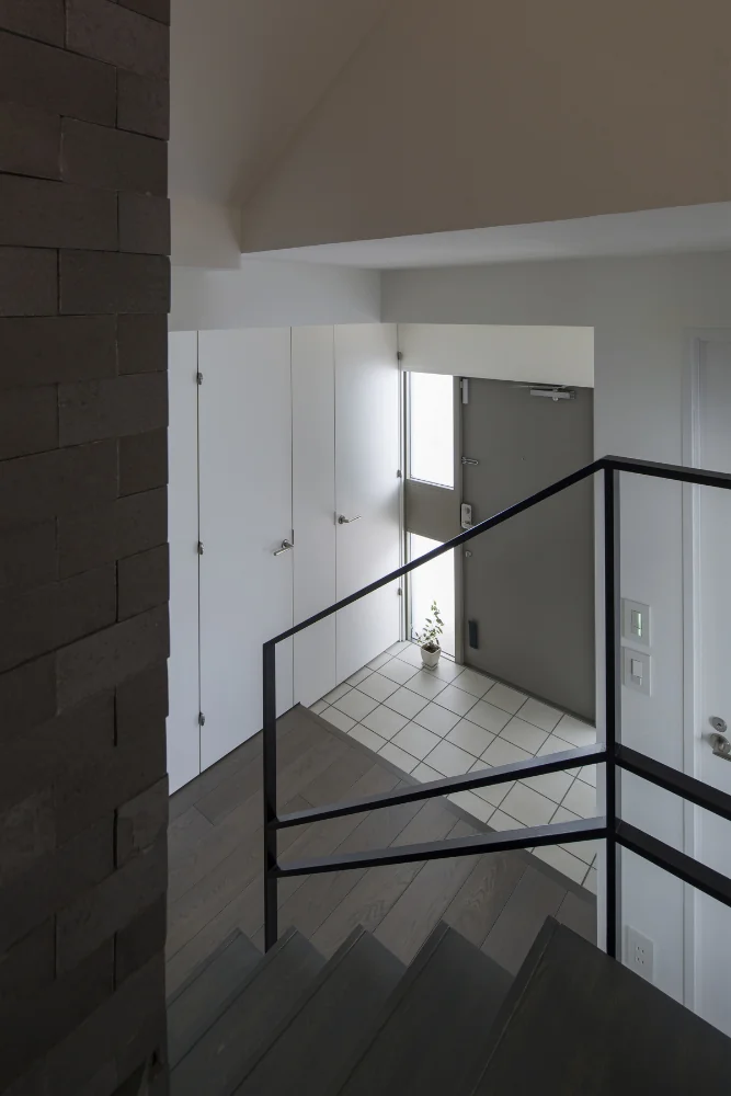 View from the stairs overlooking the entrance. A shoe closet is located adjacent to the doorway.
