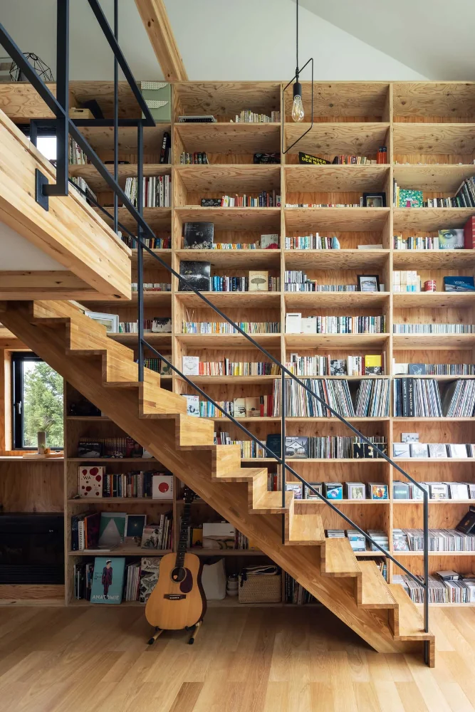 Stairs rise to the second floor from the living room’s double-height space.｜Two-Generation Residence Under One Roof | House at the Foothills of Mount Katsuragi