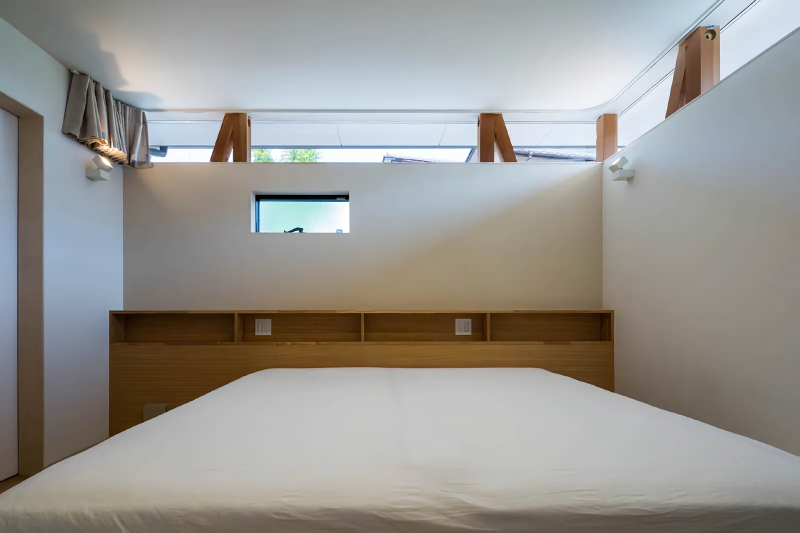 Master bedroom illuminated by light from the high-side windows on the road-facing exterior wall.