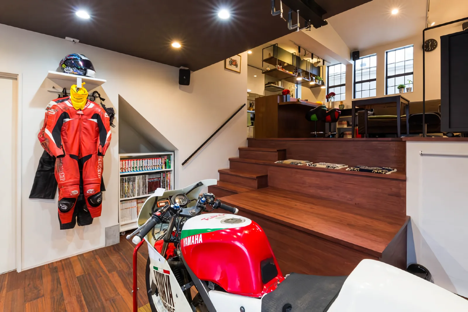 The stepped floor adjacent to the staircase serves as seating for visitors and a display area for motorcycles.