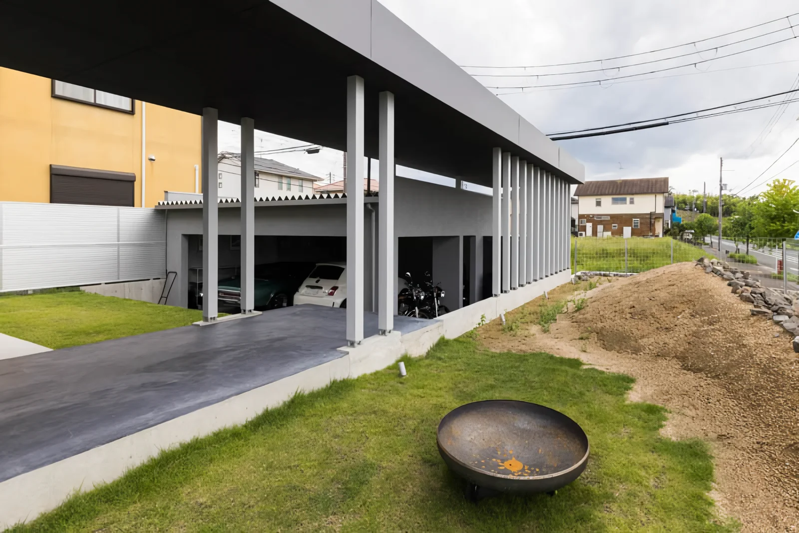 道路側の築山による外部と中庭としてのテラスの中央を縦断するアプローチ｜木津川のガレージハウス