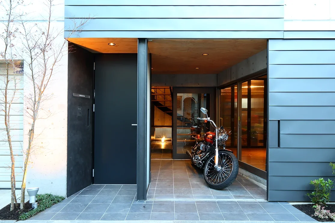 外壁同材の引戸を開くと玄関と一体のバイクガレージが現れる｜八潮のガレージハウス