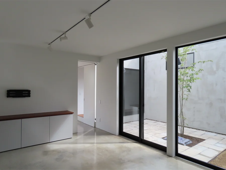 The concrete earthen floor enhances both the verdant courtyard and the displayed artworks.｜House of Earthen Floor and Cloister